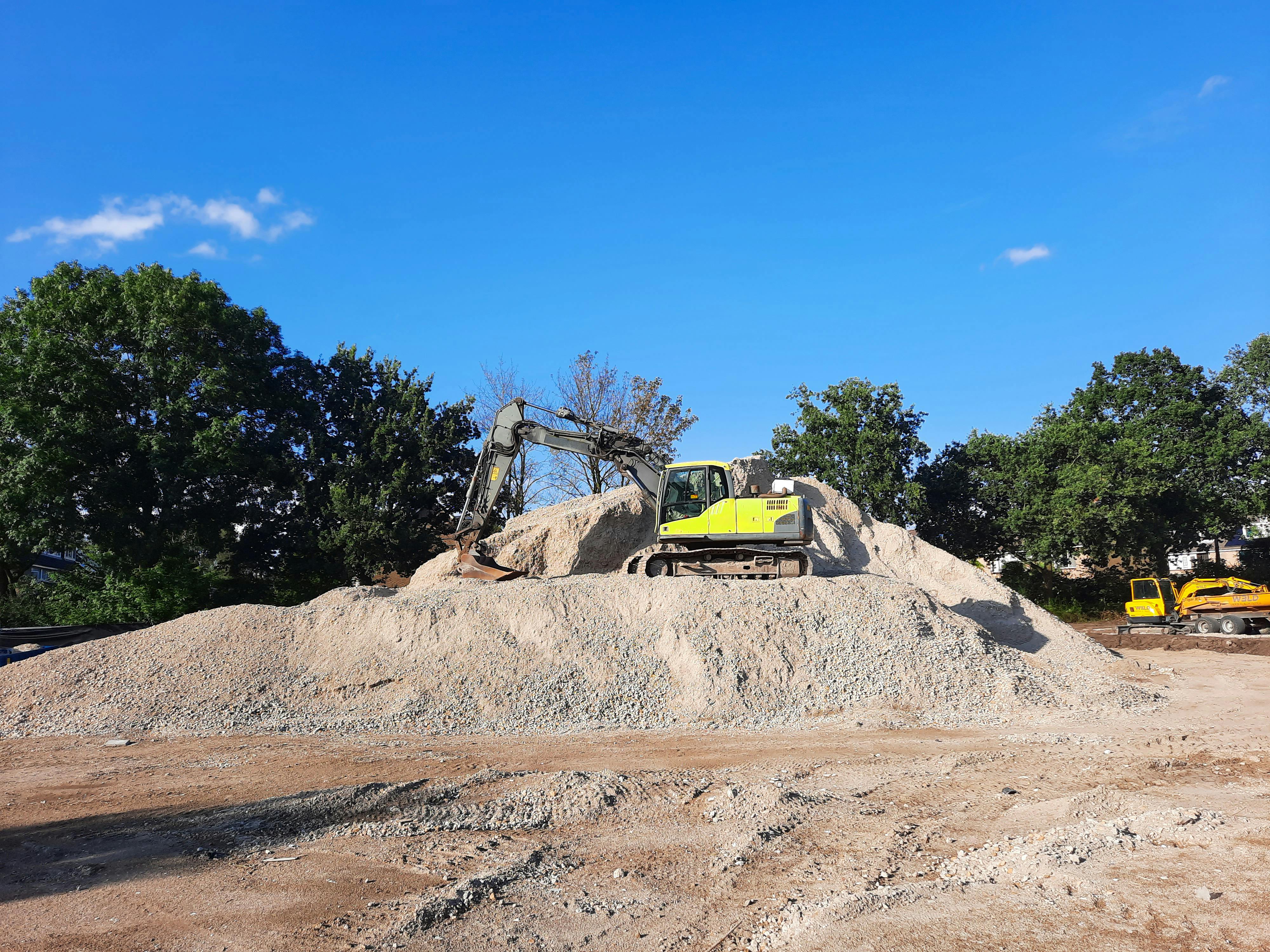 Large crushed stone stockpile with excavator